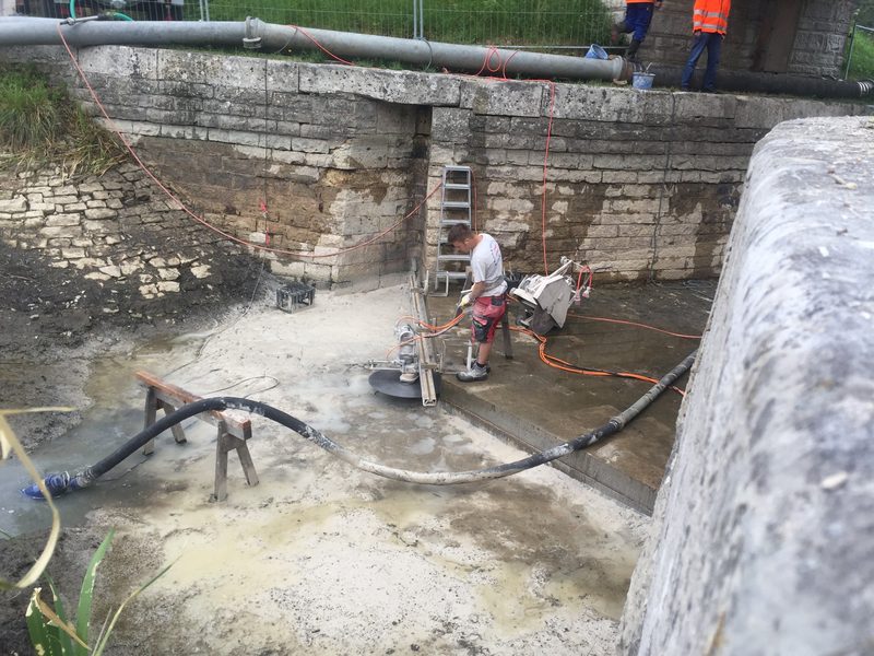 Sägearbeiten an einem Wasserbauwerk mit fließendem Wasser
